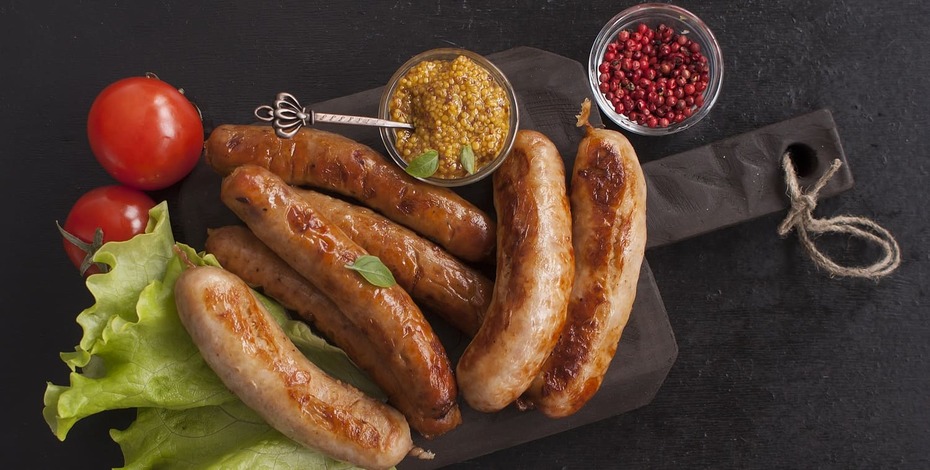 Assorted grilled delicious sausages on a wooden kitchen Board. Copy space. Top view